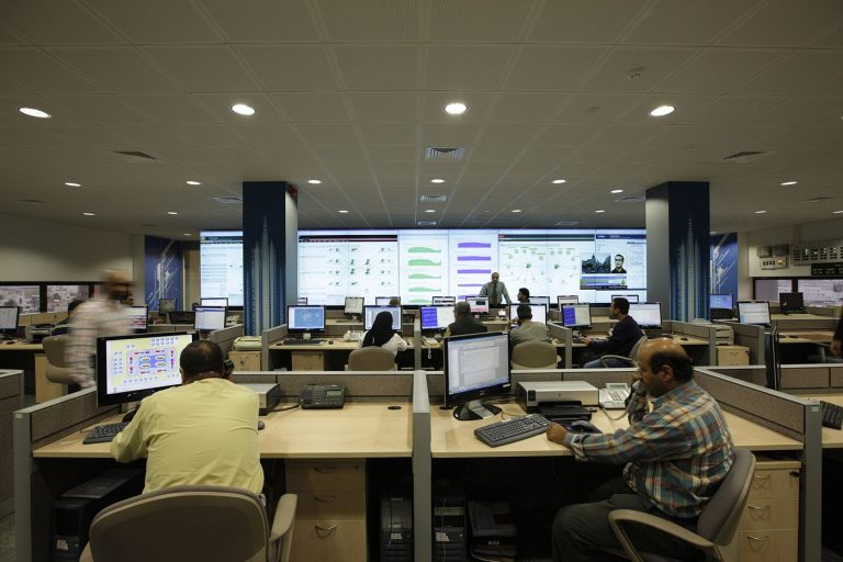 A cybersecurity analyst monitors multiple screens showing network data and security alerts.
